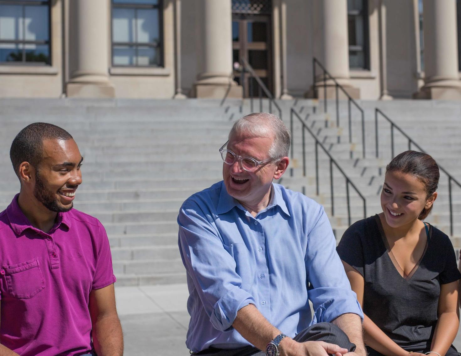 President Jacques Frémont speaking with students in front of Tabaret Hall.