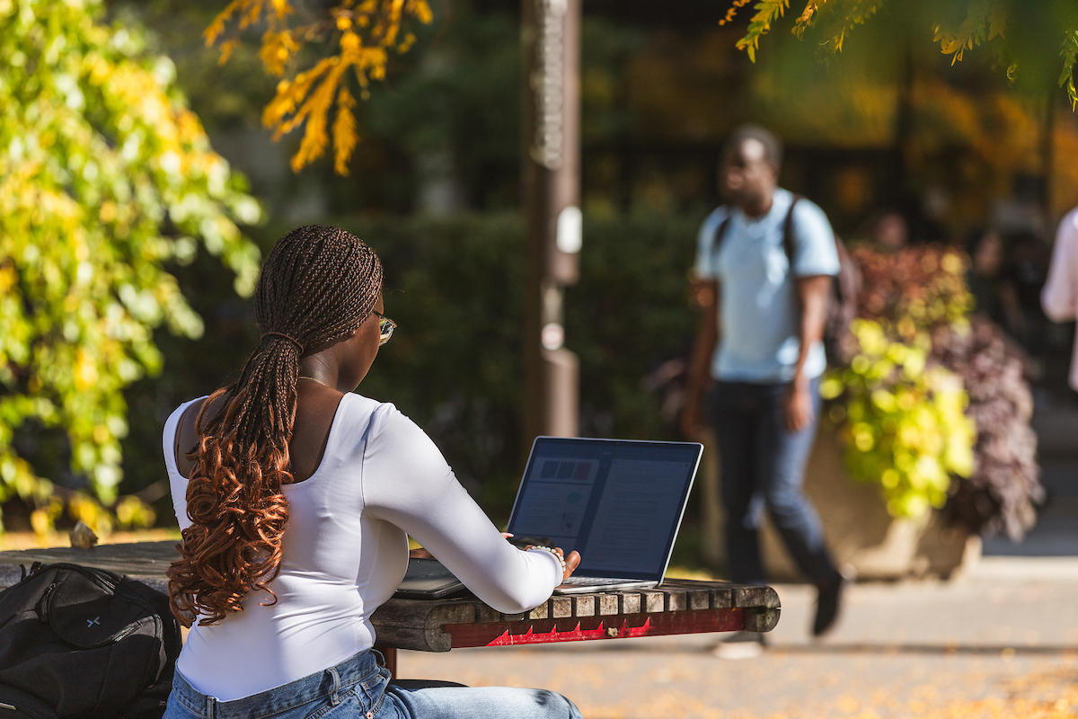 Student working on laptop outside.