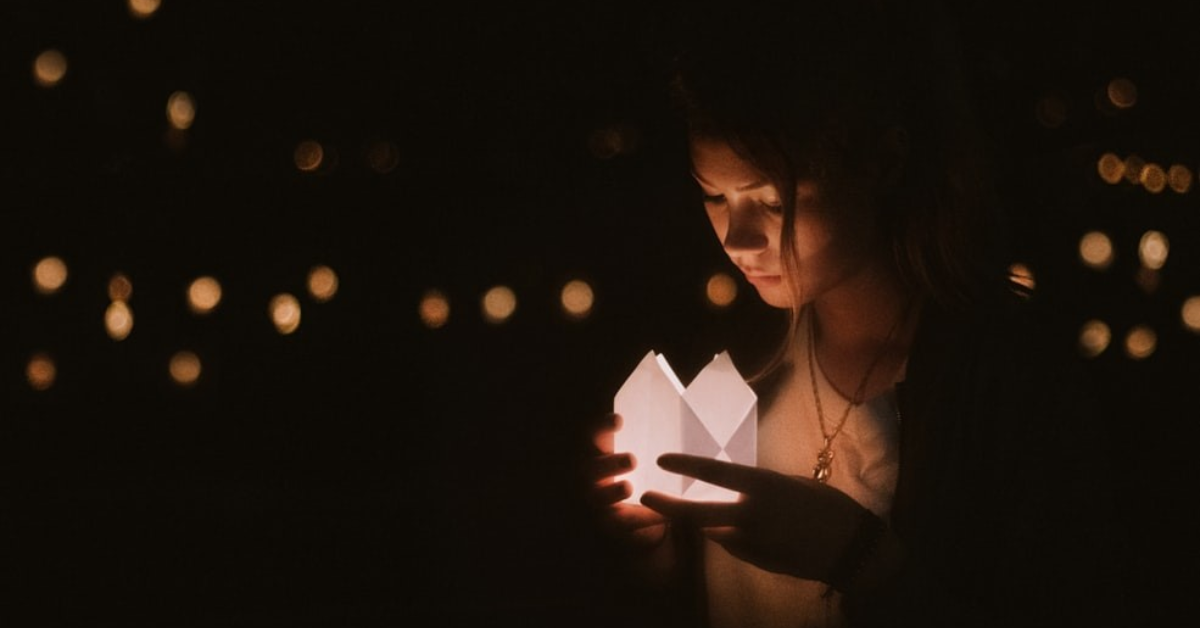 Woman holding candle during a commemorative ceremony.