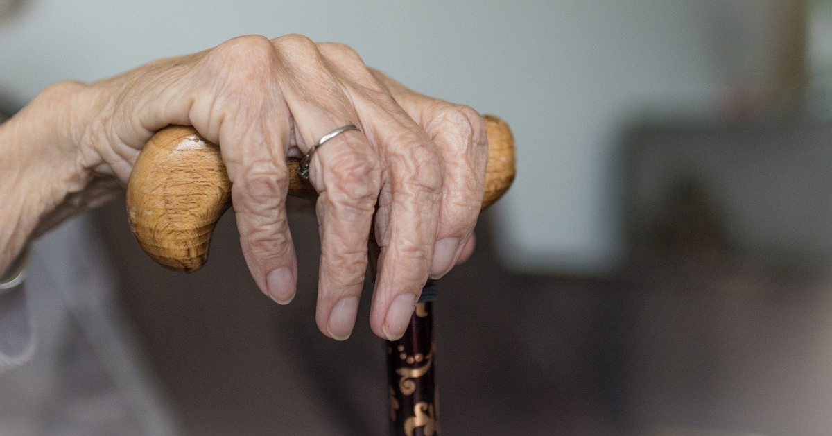 An elderly woman's hand on a cane