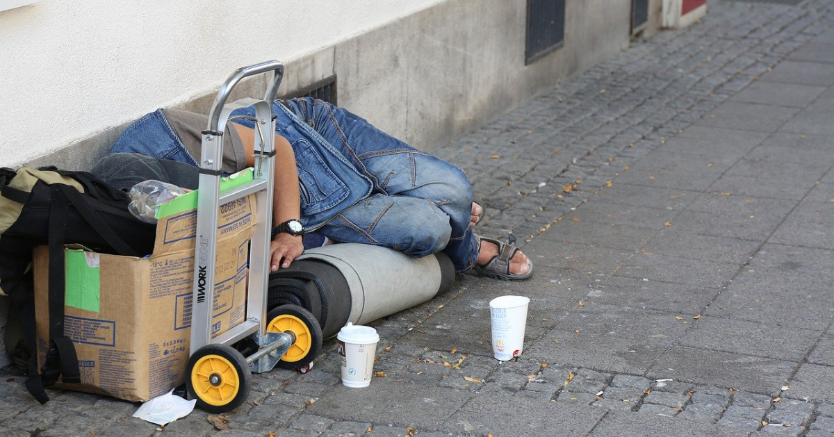A person lying on the ground with personal belongings around