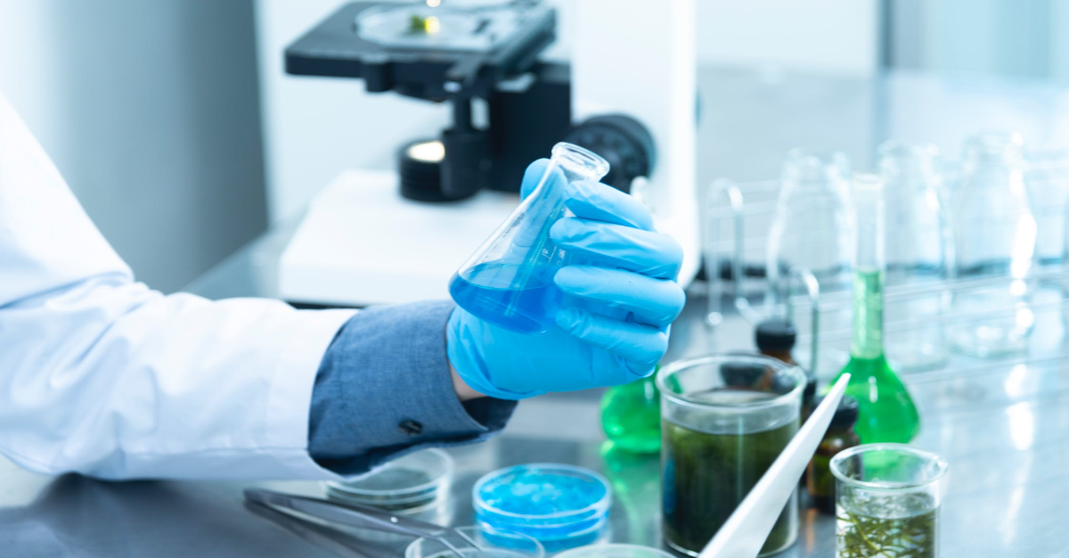 Researcher in lab holding container filled with blue liquid