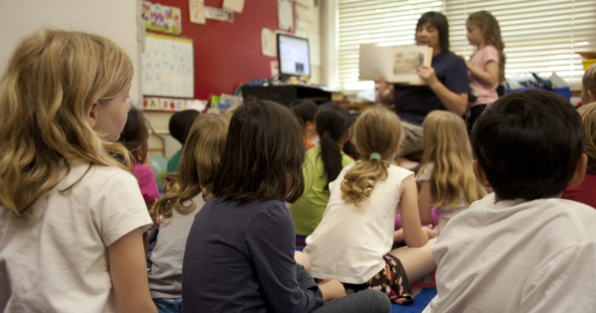 A teacher reading a book to children in a classroom