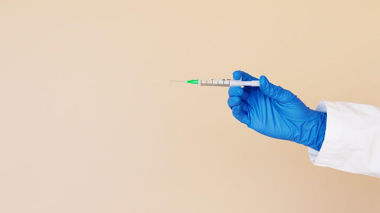 Medically-gloved hand holding needle