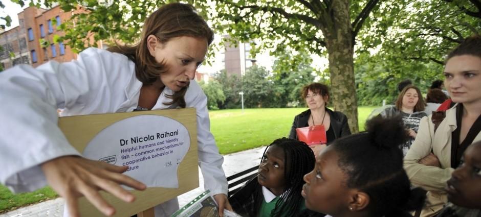 A female scientific demonstrates an experiment to kids