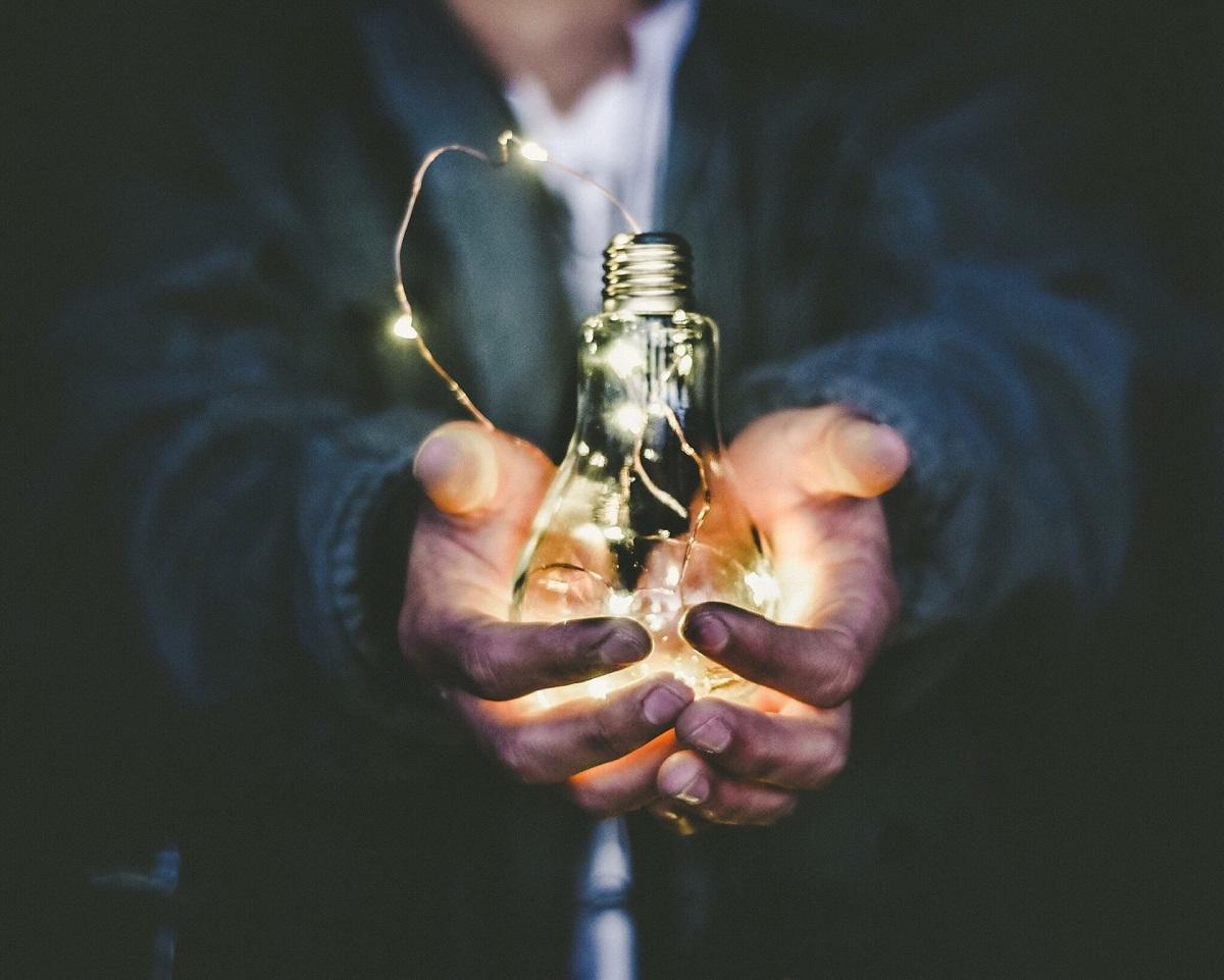 Coal stained hands holding glowing lightbulb