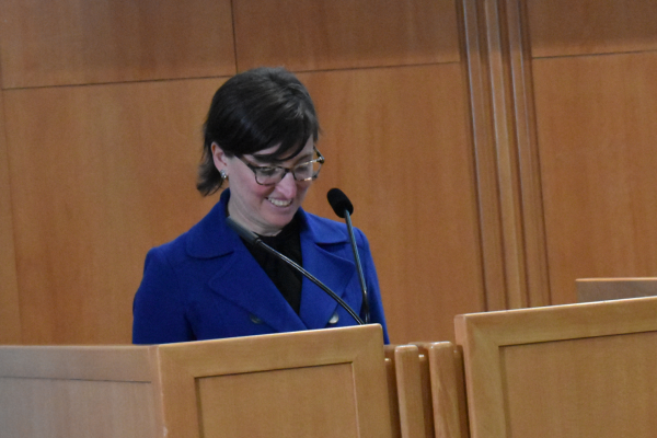 La doyenne sourit derrière le podium.