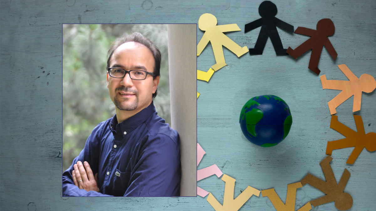 A man leans against a wall. in the background there are colourful paper cutouts of people placed around a globe