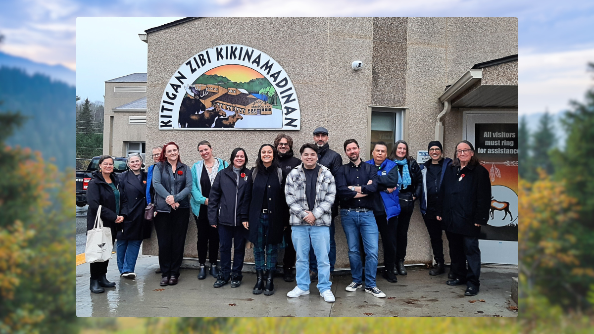 a small group of adults - students, professors and staff - stand in front of Kitigan Zibi school