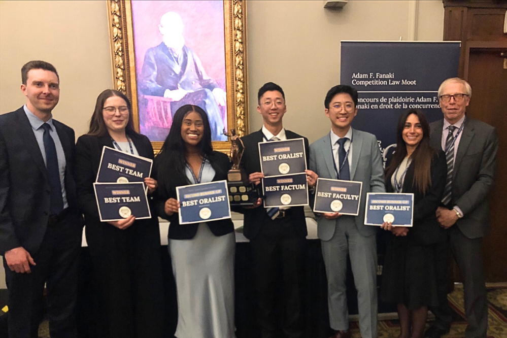 7 people, standing. The five in the middle are holding 7 certificates between them
