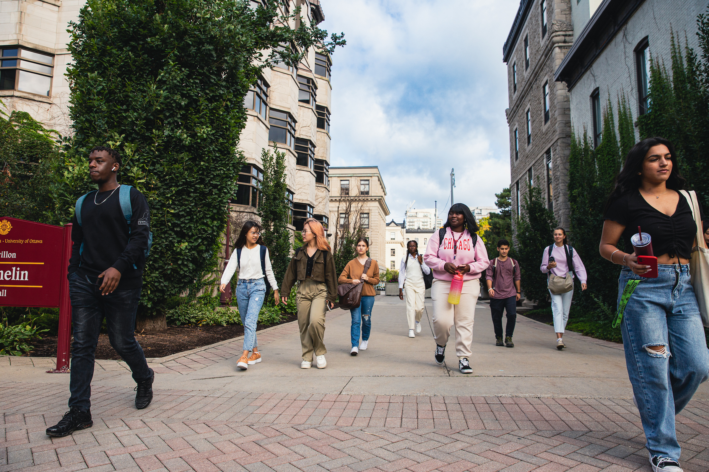 Photo des personnes qui marchent en vers la rue avec les edifices du campus visible a l'arrière-plan
