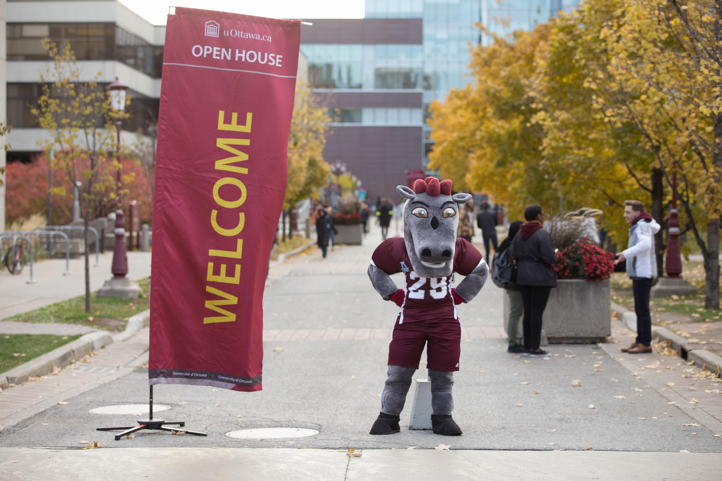 La mascotte des Gee Gees debout à côté du panneau de bienvenue.