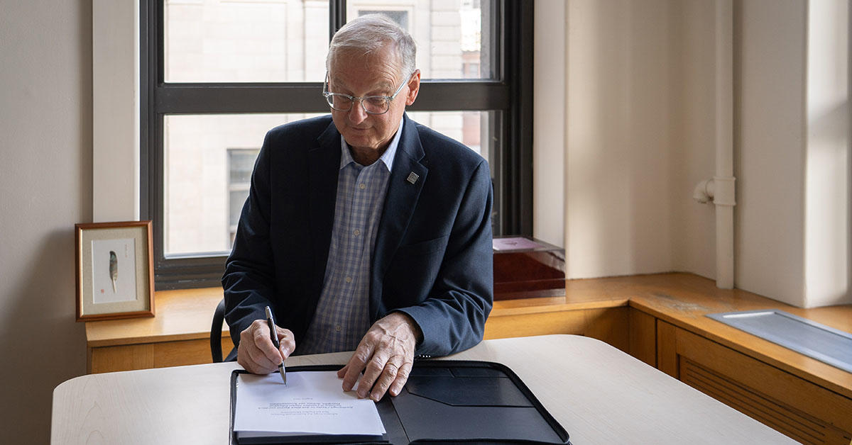 President Jacques Fremont signs the Scarborough Charter at his office.