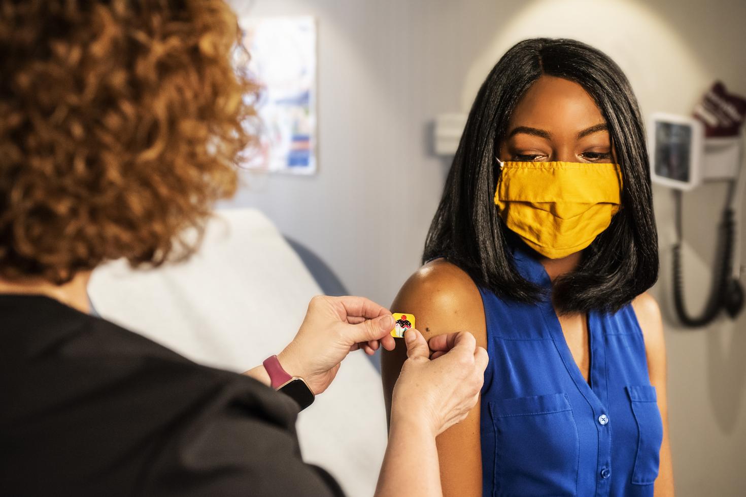 Une infirmière applique un pansement sur une femme après un vaccin