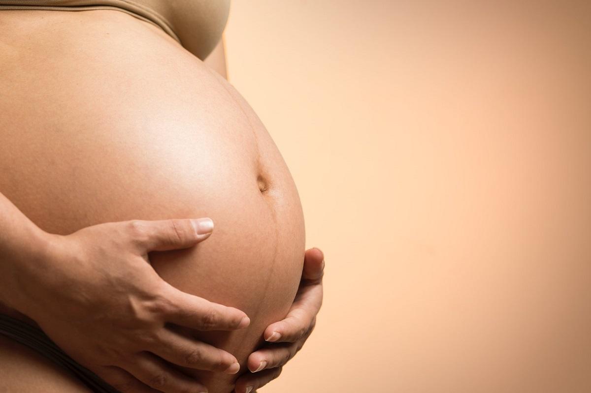 Le ventre d'une femme enceinte bercé par les mains de sa mère