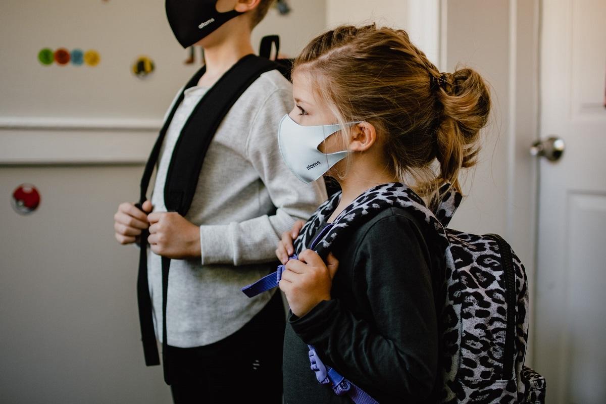 Jeune fille portant un masque et un sac à dos prête pour l'école