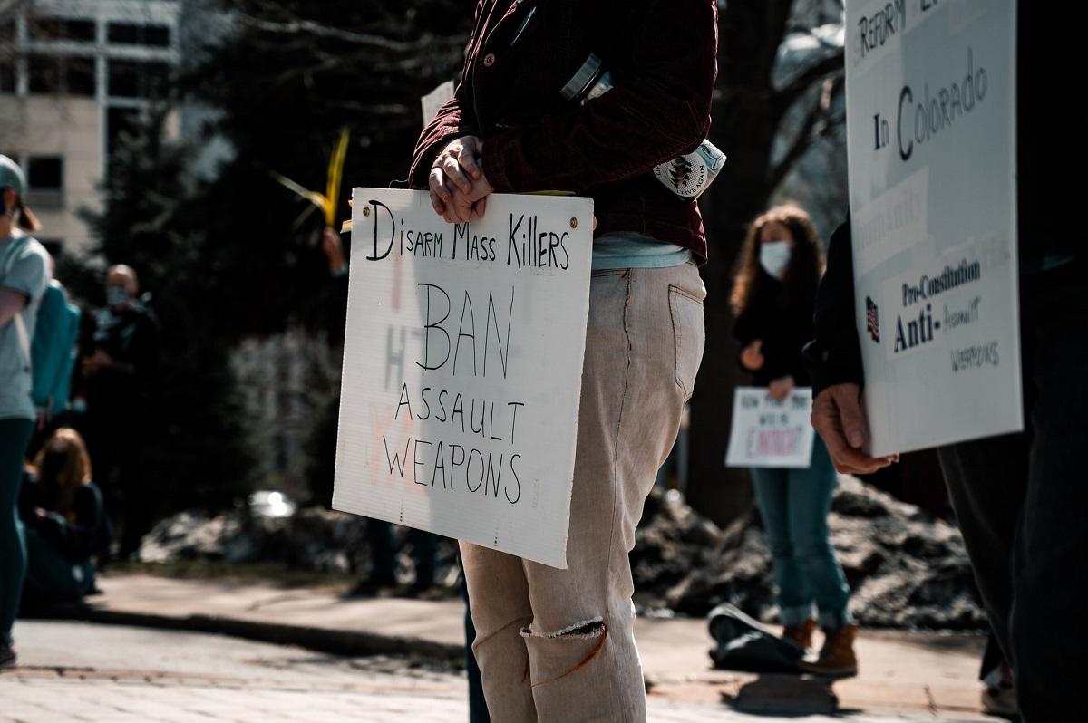 Un manifestant tient une pancarte sur laquelle on peut lire, Désarmer les tueurs de masse - Interdire les armes d'assaut