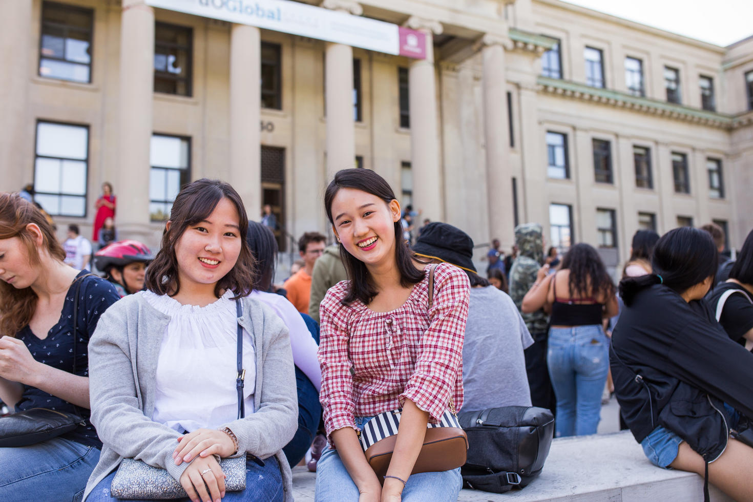 Students sitting in front of building on campus