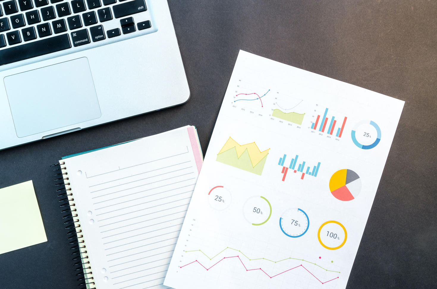 Ordinateur portable, bloc-notes et tableaux sur le bureau.