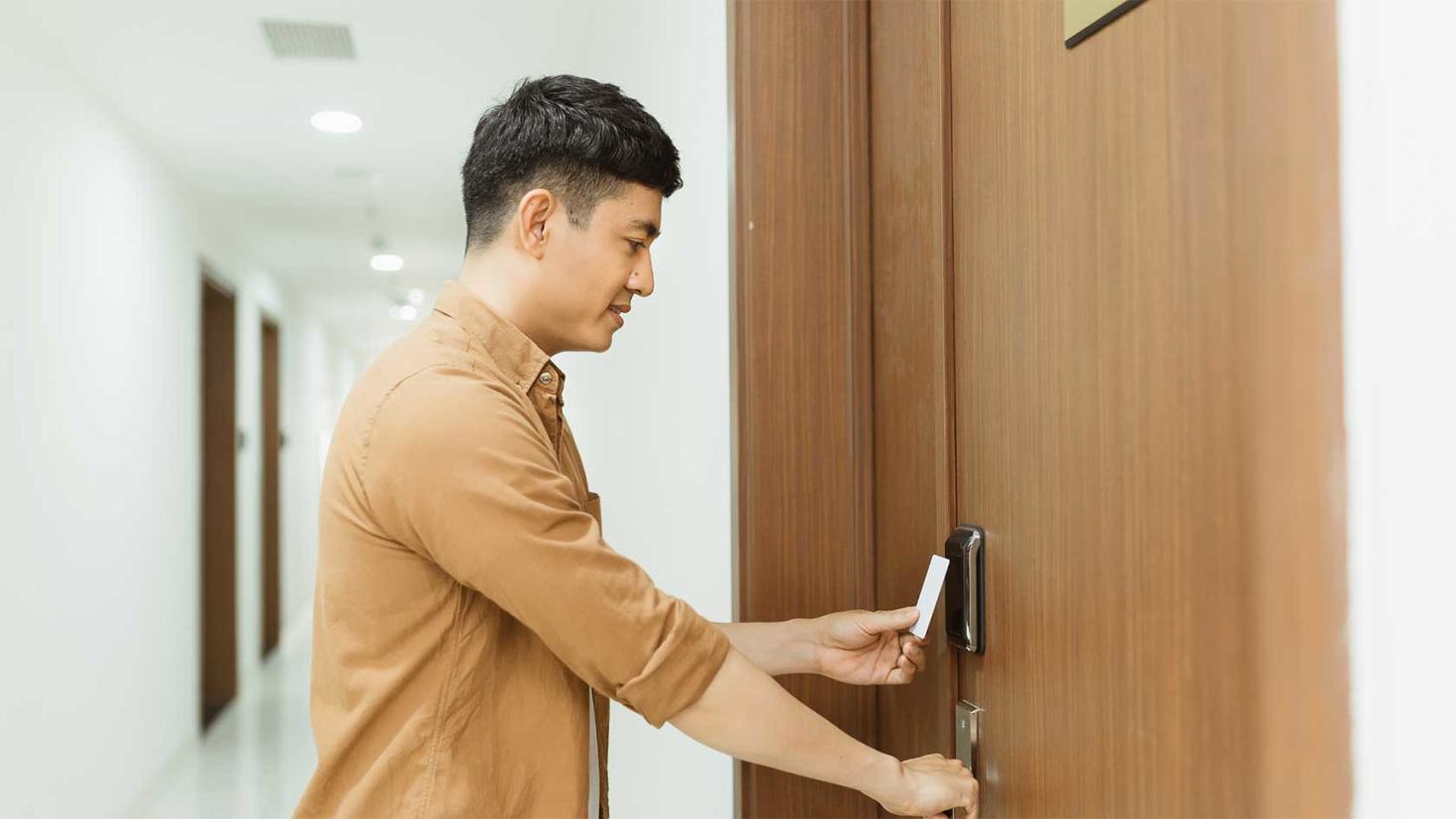 Un étudiant utilise sa carte pour débarrer la porte de sa chambre.