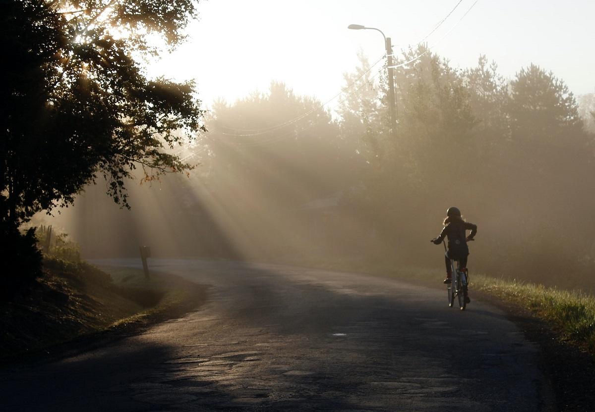 Vue d'un enfant à vélo sur la route vers le soleil du matin