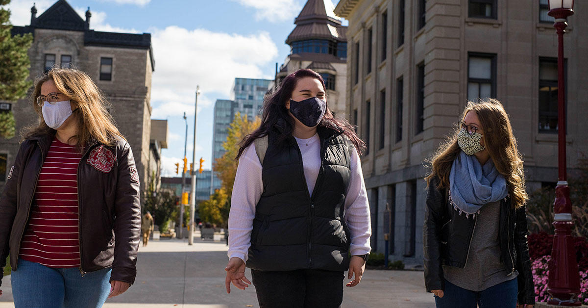 3 étudiants portant des masques marchent sur le campus de l'Université d'Ottawa
