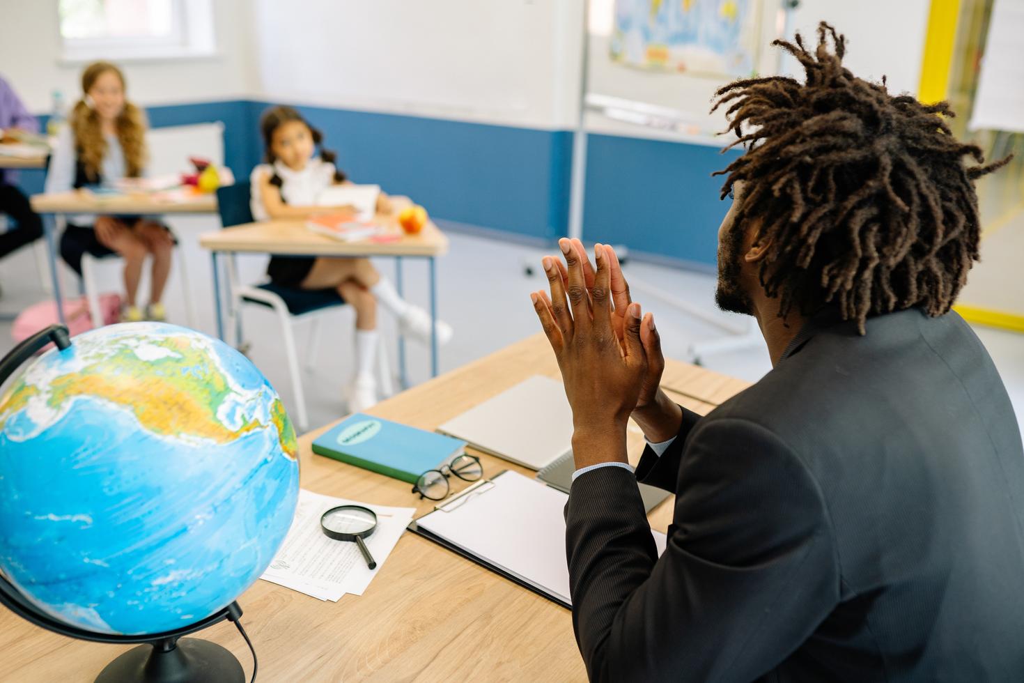 Enseignant au bureau s'adressant à des élèves du primaire