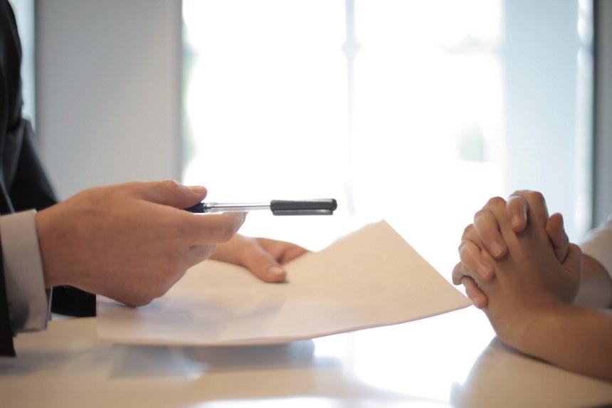 Two people's hands over a form and holding a pen