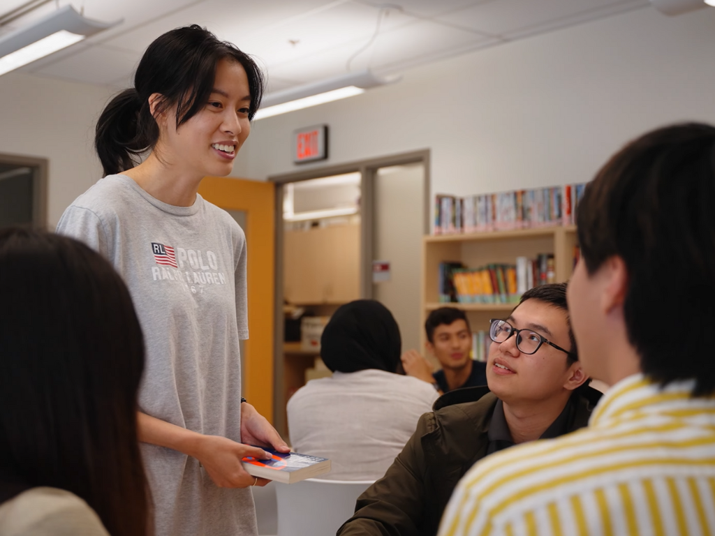 Un assistant d’enseignant parlant à un groupe d’élèves dans une bibliothèque.