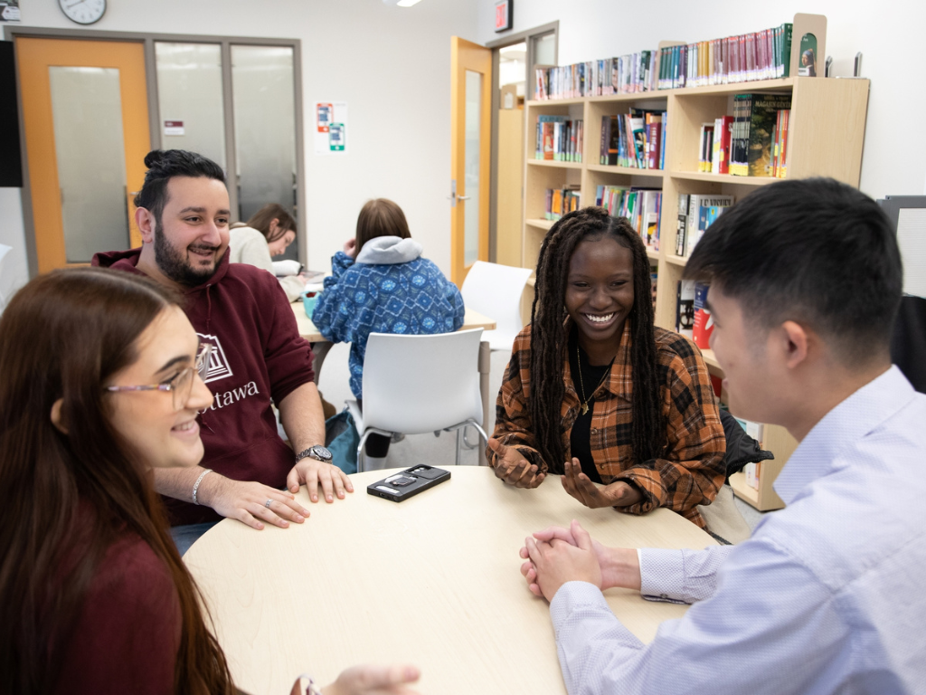Students sitting together at a table and laughing at the Julien-Couture Resource Centre