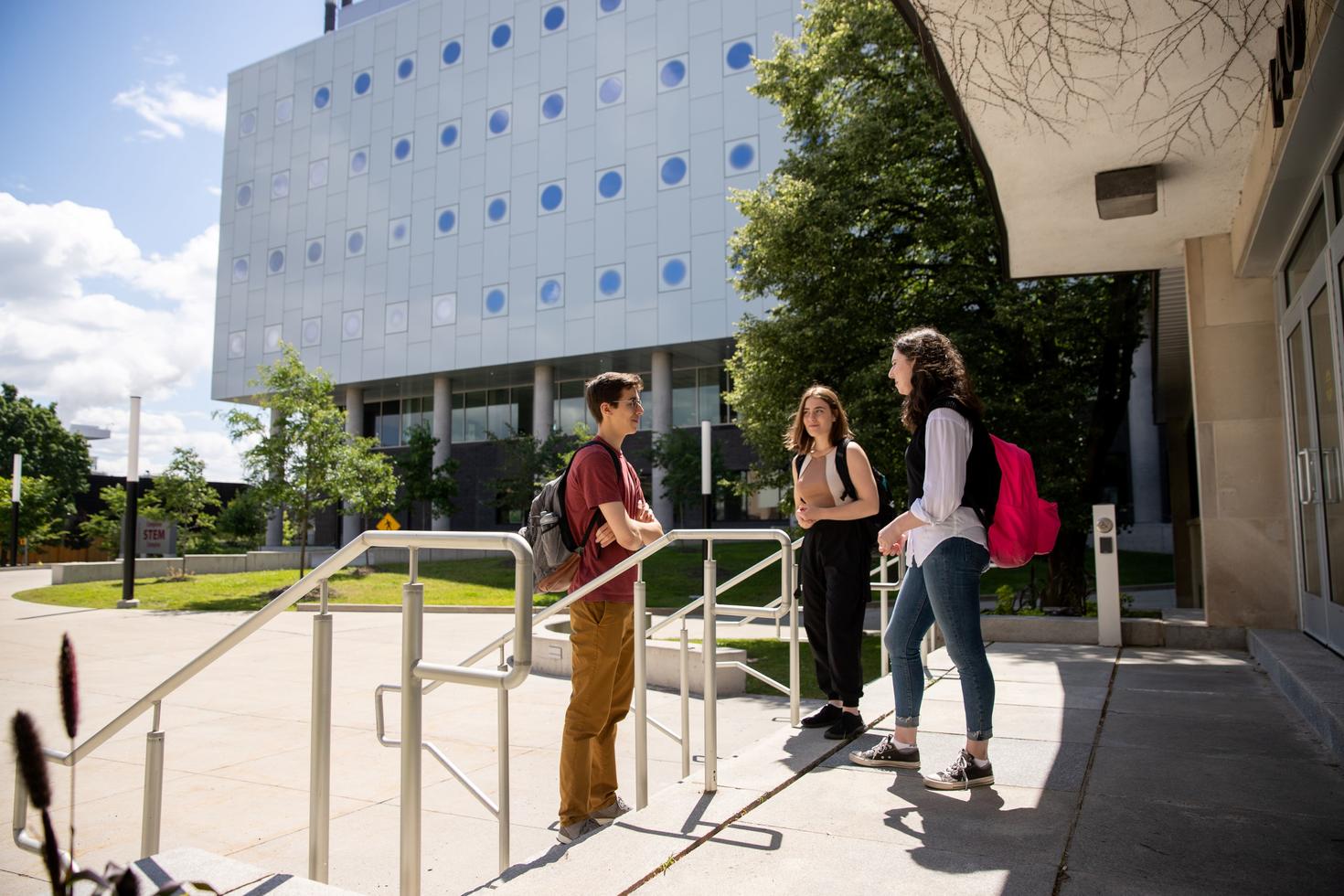 Trois étudiants devant la faculté des sciences sociales d'Uottawa