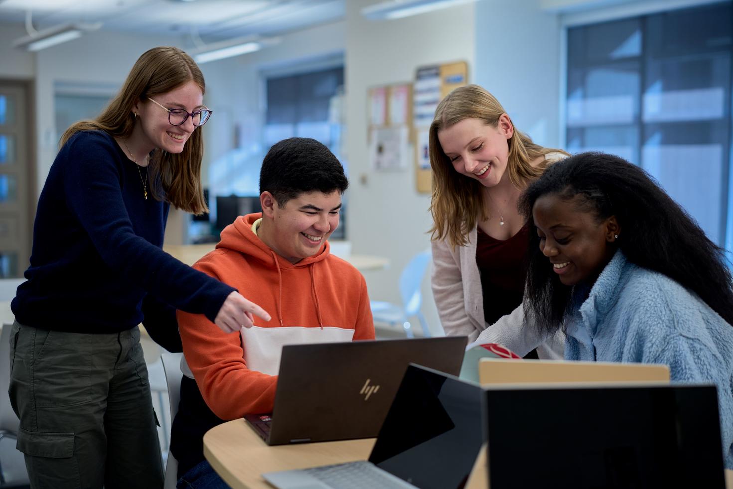 Quatre étudiants autour d'une table sur des ordinateurs portables au Centre de ressources Julien-Couture.