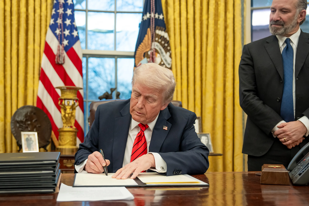 Trump en train de signer un document dans le Bureau ovale