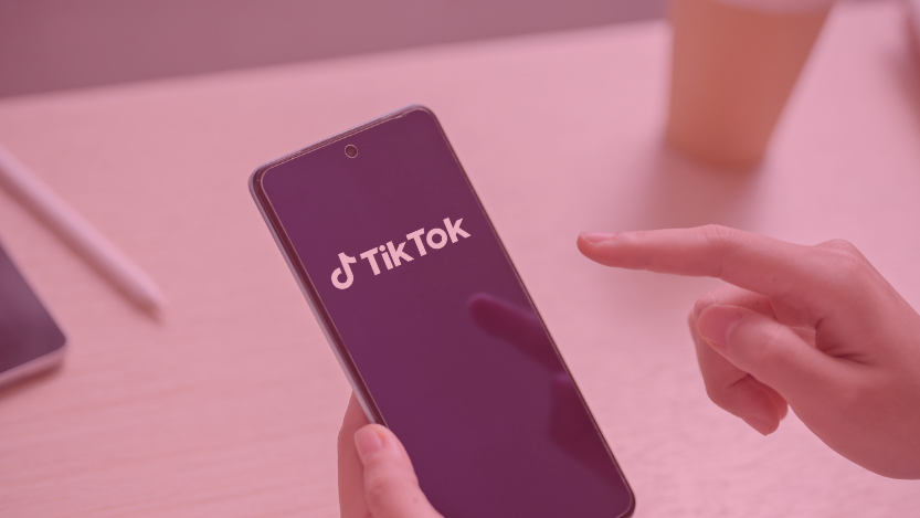 Une main tient un smartphone sombre affichant le logo « TikTok »