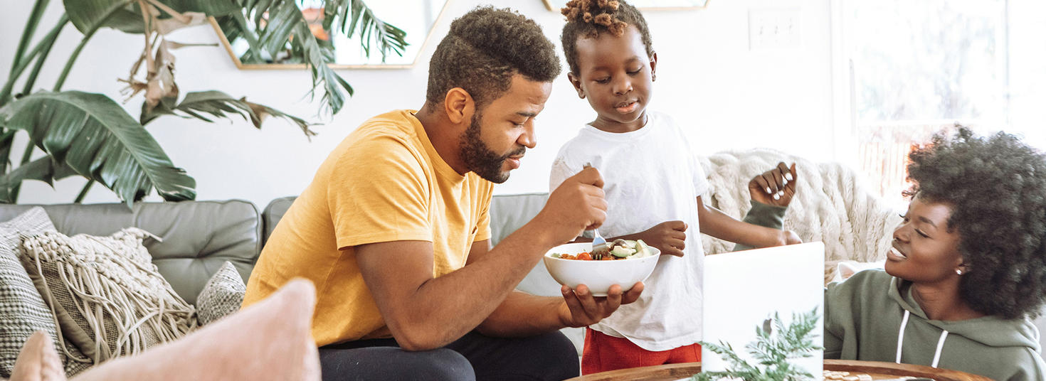 Une famille heureuse en train de manger sur le sofa