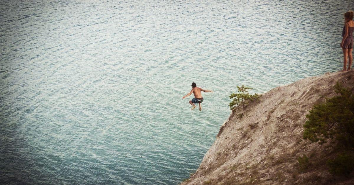 Homme sautant d'une falaise dans un plan d'eau