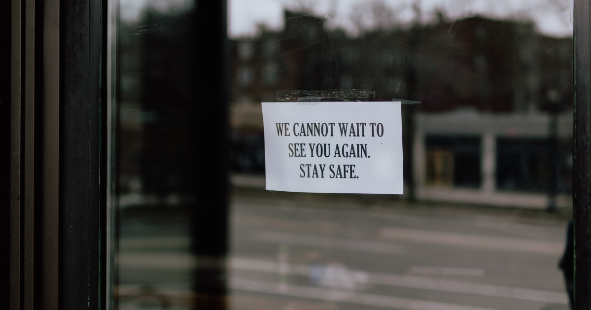 Un signe sur la porte d'entrée d'un commerce ''We cannot wait to see you again. Stay safe.''
