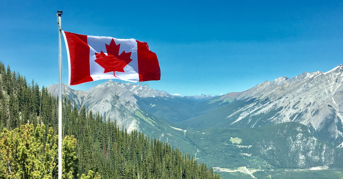 Drapeau du Canada devant des montagnes.