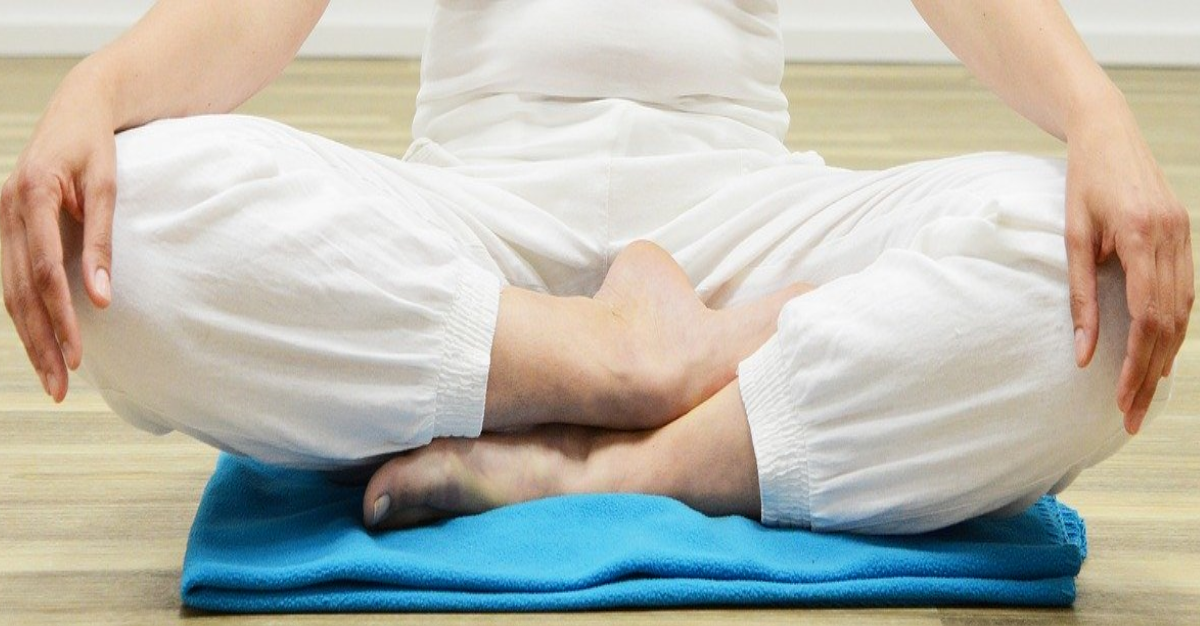 Personne assise avec les jambes croisées et les bras étendus