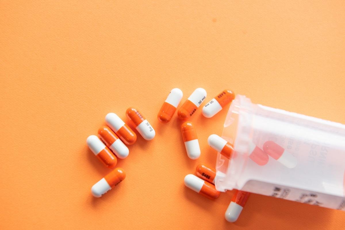 des pilules orange et blanches débordant du flacon