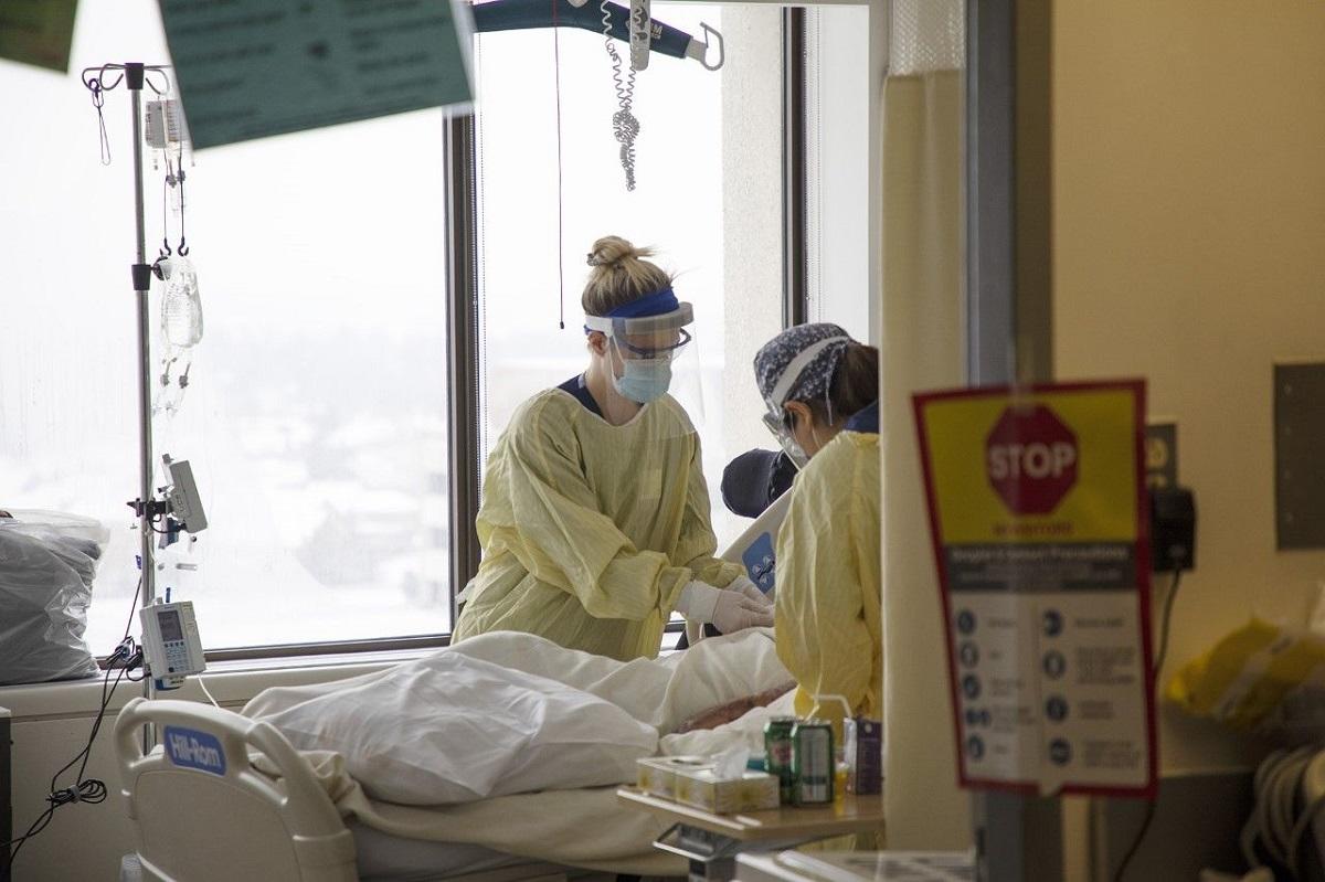 Deux professionels de santé en EPI autour de le lit d'un patient à l'hôpital
