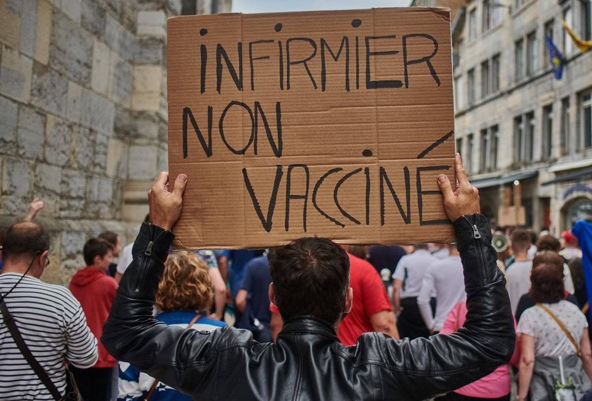 Vue de dos d'un manifestant tenant une pancarte française sur laquelle on peut lire 