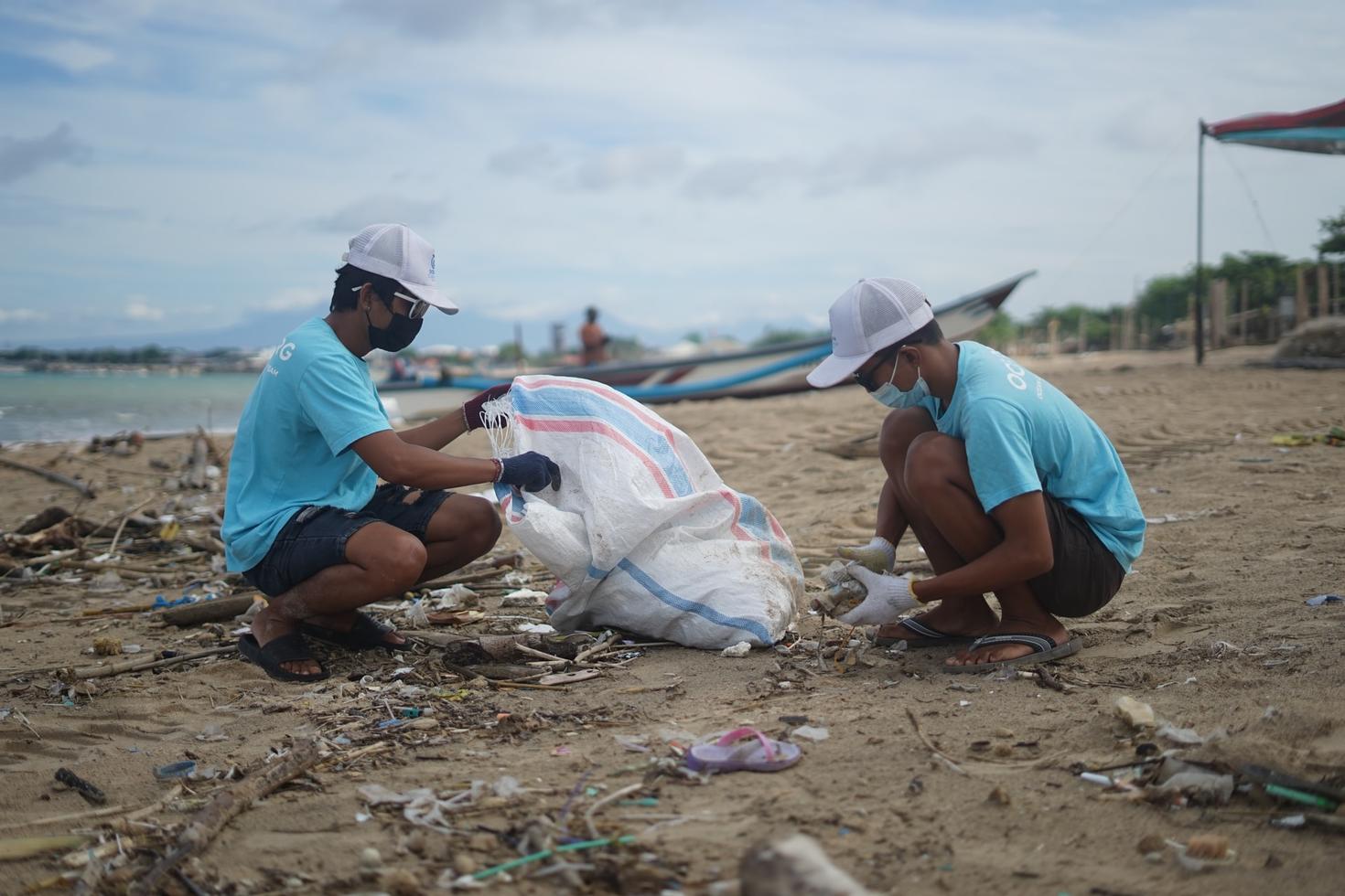 Deux travailleurs ramassent des déchets d'une plage