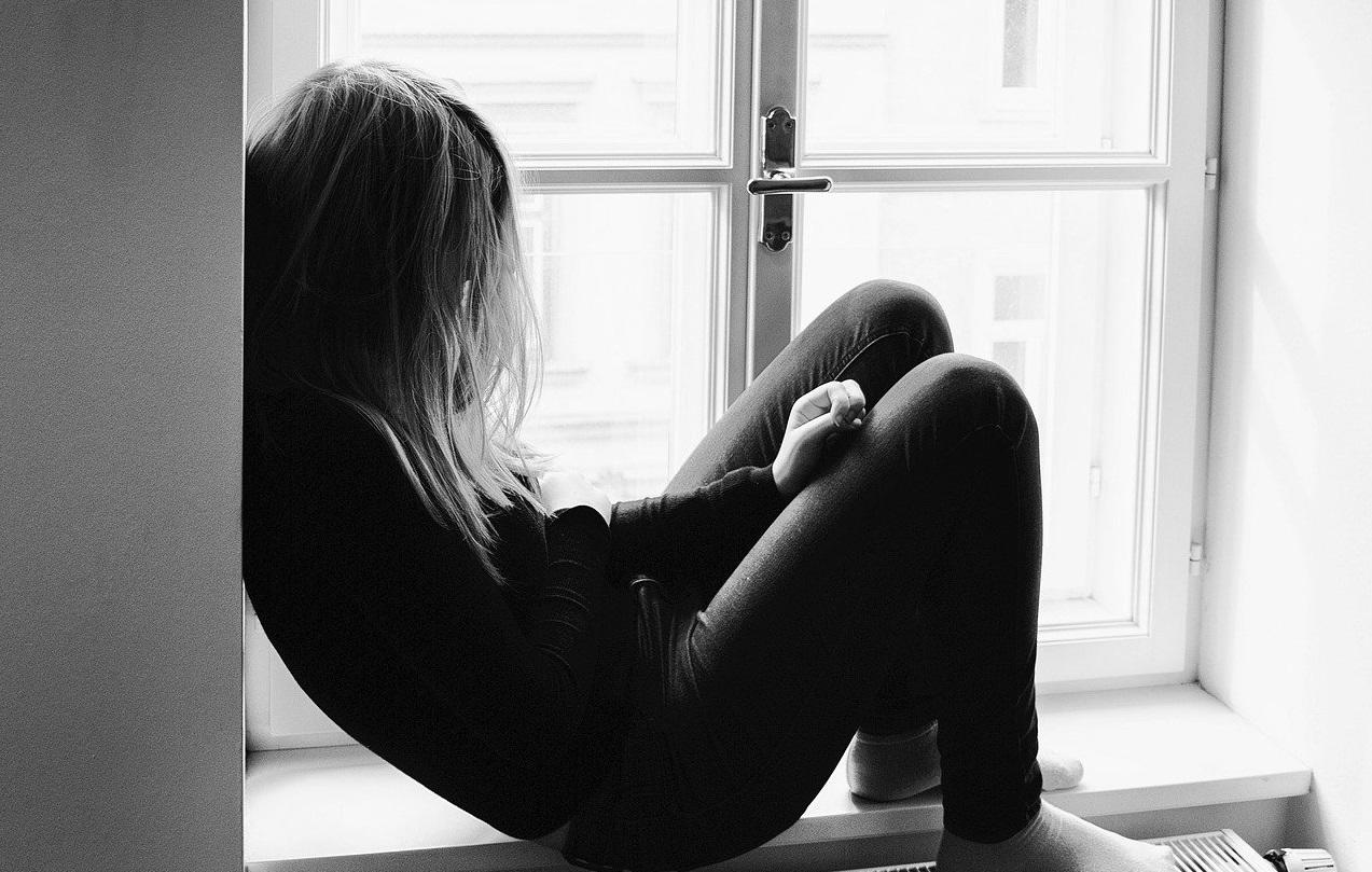 Photo noir et blanc d'une adolescente assise devant la fenêtre