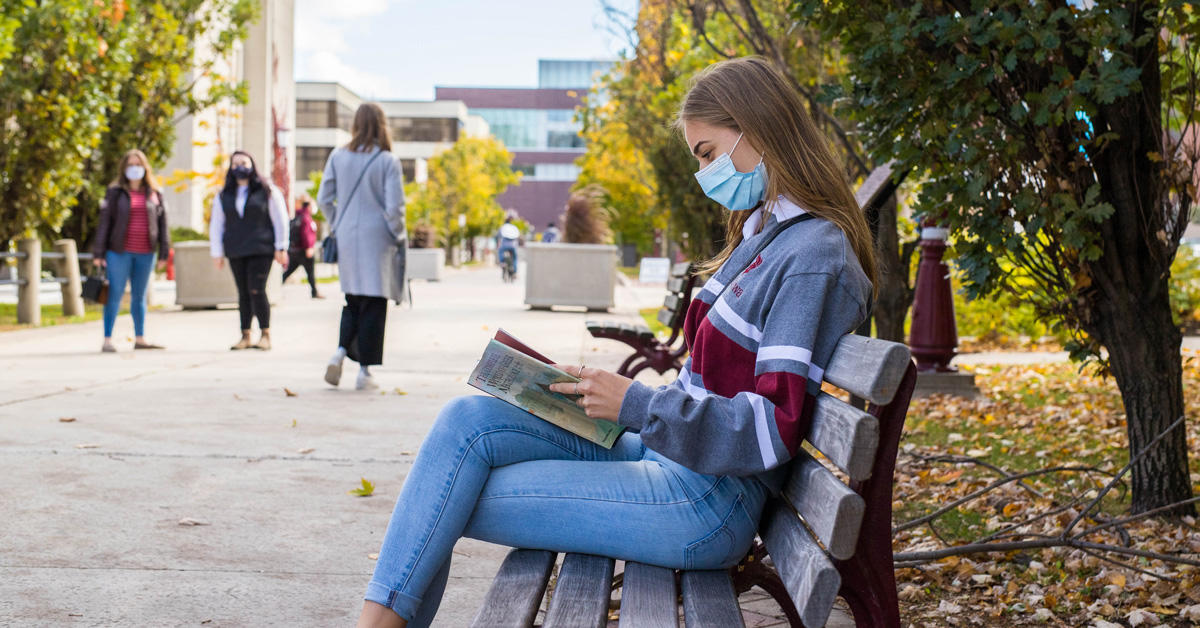 A student reads a book outside on campus.