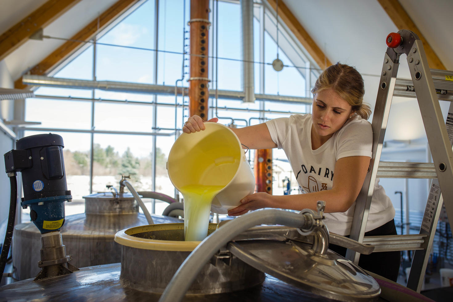 A woman pouring out a liquid into a large tank 