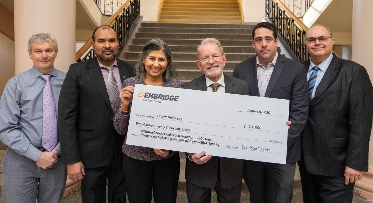 A group of dignitaries hold the giant cheque presented by Enbridge Gas to the University of Ottawa, with the amount of $220,000 written on it.
