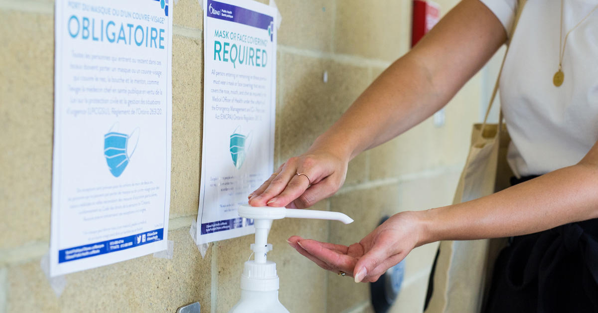 A person presses a hand sanitizing gel pump.