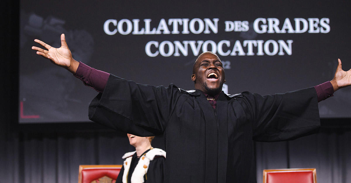 diplômé acclamant sur scène avec les bras écartés