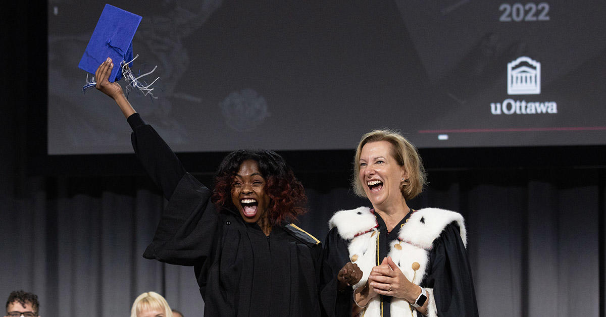 Un diplômé en sciences sociales applaudit sur scène lors de la cérémonie de remise des diplômes.
